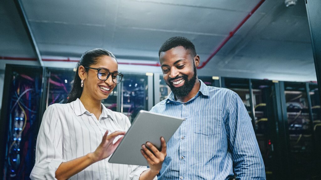 Shot of two young technicians using a digital tablet while working in a server room | Prise de vue de deux jeunes techniciens utilisant une tablette numérique alors qu'ils travaillent dans une salle de serveurs