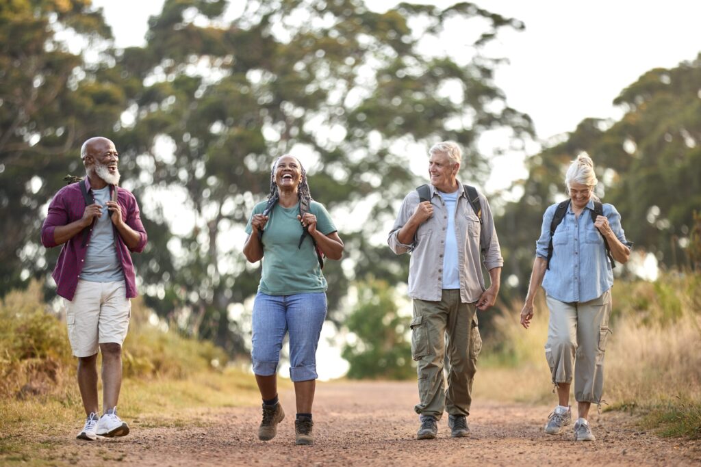 Group Of Active Senior Friends Enjoying Hiking Through Countryside Walking Along Track Together | Groupe d'amis seniors actifs appréciant la randonnée à travers la campagne en marchant le long de la piste ensemble