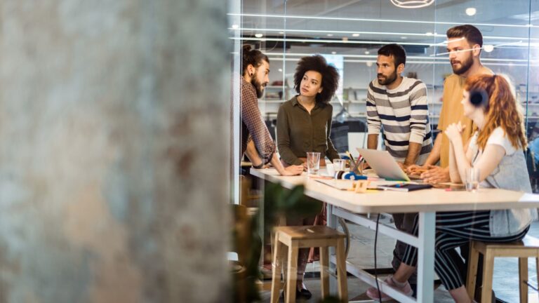 A diverse group of individuals engaged in conversation around a table, fostering collaboration and connection.