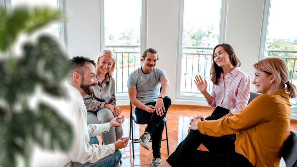 A diverse group of people sitting in a circle, engaged in conversation and sharing ideas with one another.