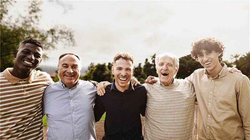 A group of five men share smiles and laughter, enjoying each other's company.