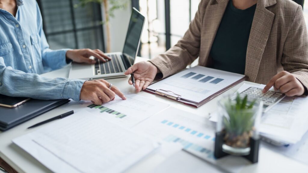 Business professionals collaborating on paperwork at a desk, focused on figuring ROI of mental health training