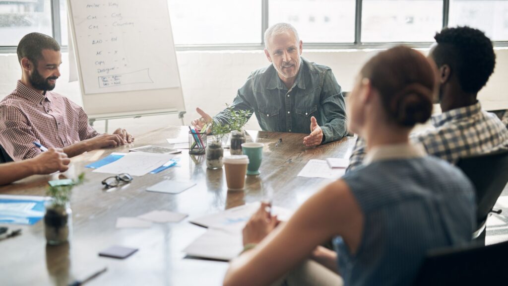 A diverse group of people engaged in conversation around a table, sharing ideas and collaborating on a project.