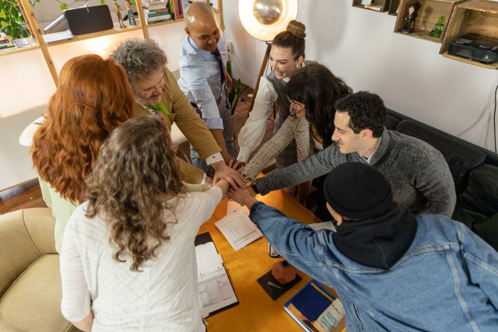A diverse group of coworkers collaborating around a table in a modern office, representing workplace wellbeing through connection and teamwork.