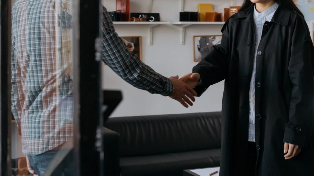Two colleagues shaking hands in an office, symbolizing a collaborative accommodation agreement
