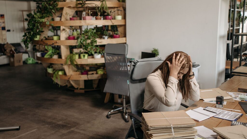 A stressed employee overwhelmed by paperwork at a desk, illustrating workplace stress