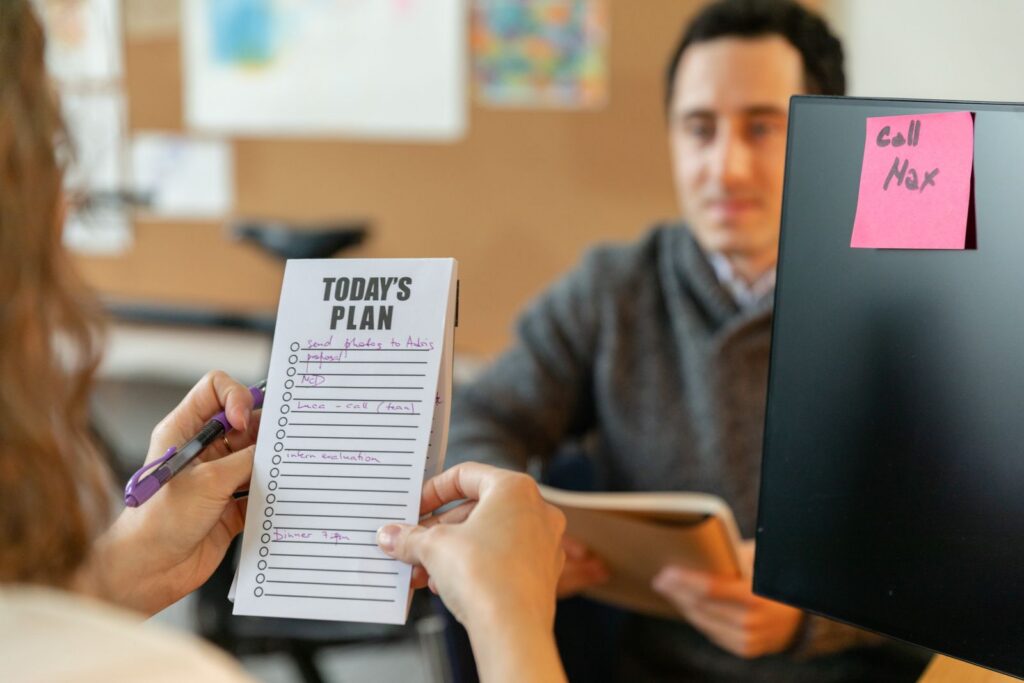 Two colleagues reviewing an absence tracking plan with sticky notes during a team meeting