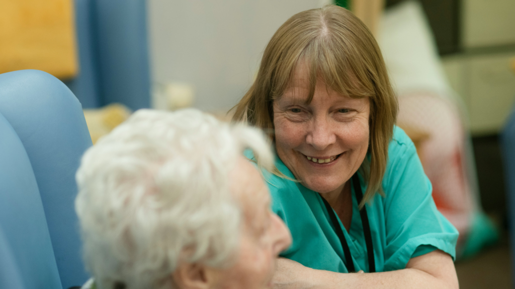 Smiling healthcare worker in scrubs comforting an elderly patient