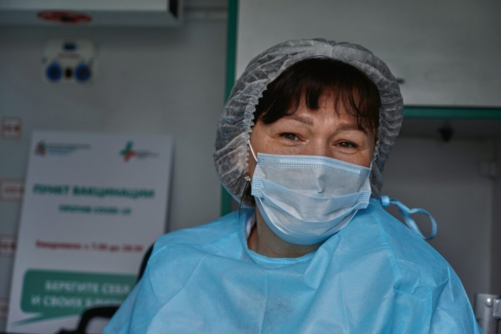 Healthcare worker wearing a surgical mask, hair cover, and protective gown